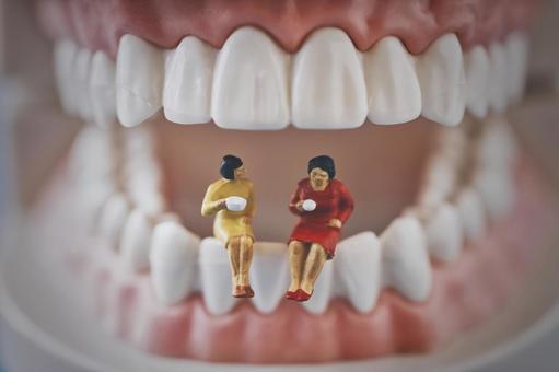 歯ぐきの模型の上で人形が談笑しているイラスト